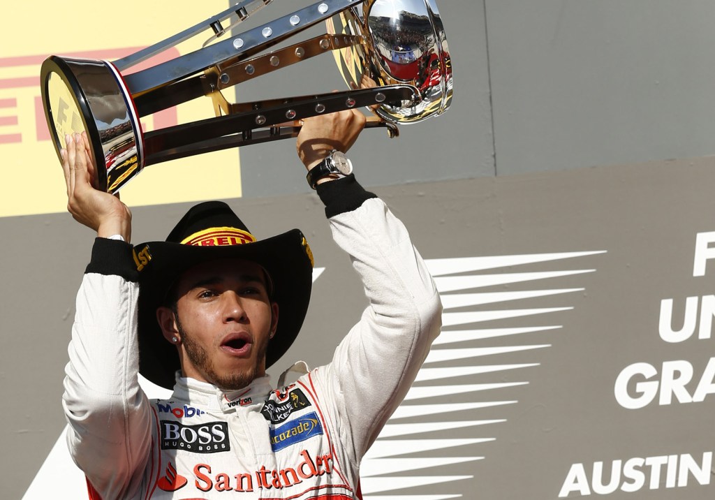 Lewis Hamilton raising his trophy over his head in celebration